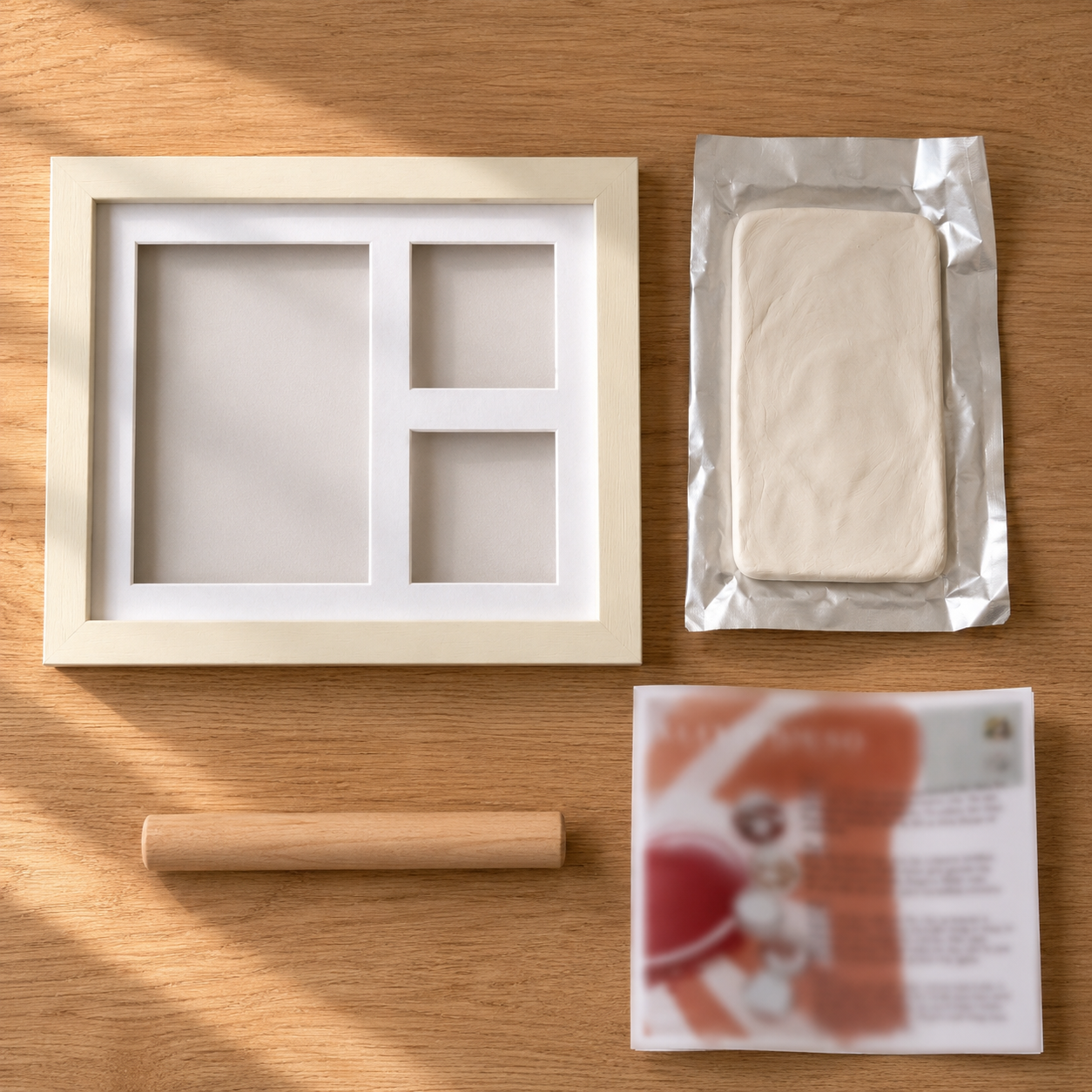 Kit desarmado: marco, arcilla, rodillo e instructivo sobre una mesa de madera